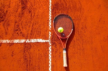 Ein Tennisschläger und ein Ball auf dem Spielfeld.