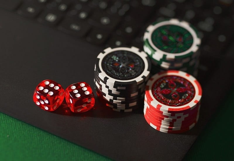 Pokerchips und Spielwürfel auf einem Laptop.