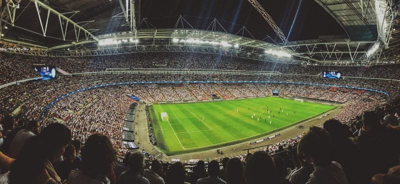 Ein vollbesetztes Fußballstadion mit zwei spielenden Teams.