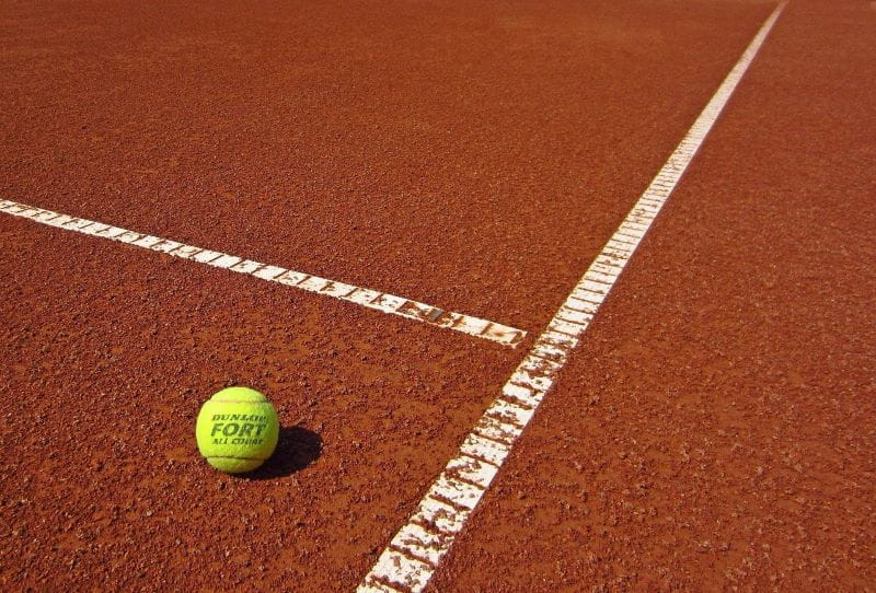 Ein Tennisball liegt allein auf dem Spielfeld.